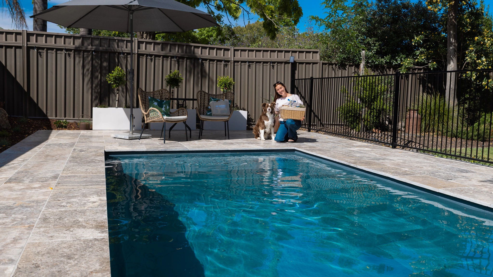 The Precision 6.00m fibreglass swimming pool is installed in front of a white countryside farmhouse, with greenery and mountains surrounding it. The mysterious Graphite Grey gives a modern look to the overall countryside aesthetics.