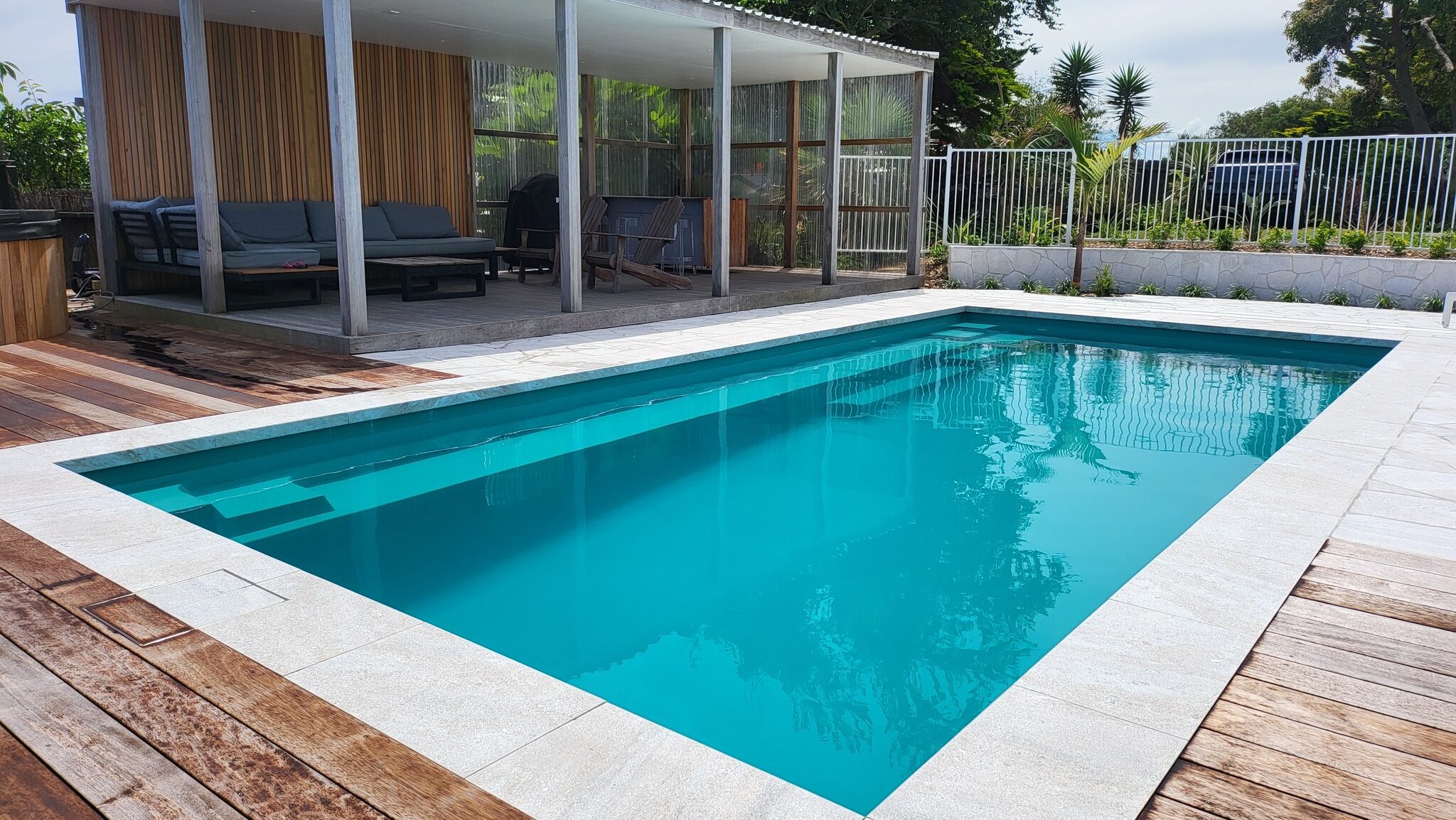 The Reflection 8.00m fibreglass swimming pool is installed in an ocean-view house, with greenery complementing its surroundings. Its Aquamarine colour stands out from the seawater of Kapiti, New Zealand.